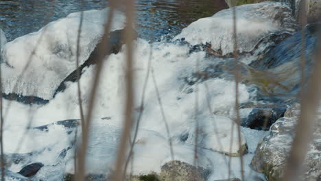 flowing-frozen-river-with-water-foam,-medium-shot,-slow-motion