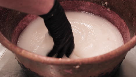 Hand-In-Black-Gloves-Mixing-Sugar-And-Water-In-A-Container