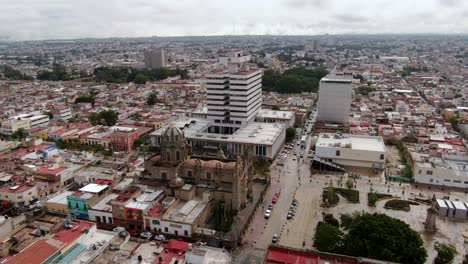 Aerial-View-Of-Traffic-Passing-By-Sanctuary-Of-Our-Lady-Of-Guadalupe,-Shrine-Garden-And-Federal-Palace-In-Guadalajara,-Mexico