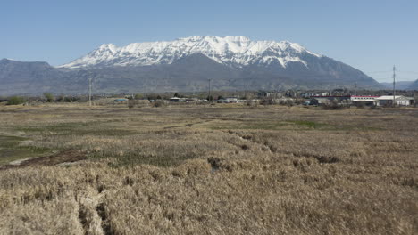 Drone-shot-of-Powell-Slough-wetland-area-with-snow-capped-mountains-on-horizon