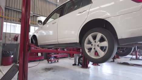 Lowering-of-a-white-car-on-a-red-car-lift-at-a-workshop-station-garage-at-mexico-latin-america