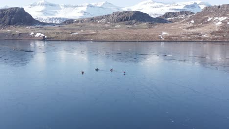 Cuatro-Kayakistas-En-Aguas-Tranquilas-Con-Superficie-Semi-Congelada-En-El-Fiordo-De-Islandia