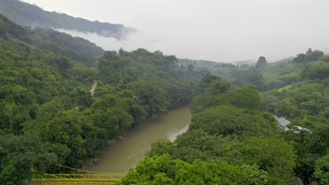 Drone-aerial-footage-of-river-Rio-Cahabon-near-Semuc-Champey-National-Park-in-Guatemala-surrounded-by-bright-green-rainforest-trees-on-a-cloudy-day-near-Chicanutz