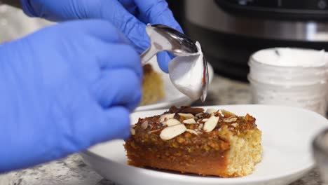 Placing-Spoonful-Of-Icing-On-Top-Of-Banana-Caramel-Cake-Slice