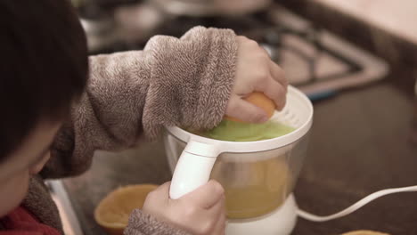 Asian-kid-making-natural-fresh-squeezed-orange-juice-by-himself