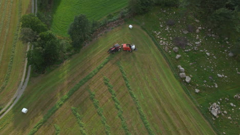 Tractor-with-baling-machine-making-silage-bales-on-farmland,-Scandinavia