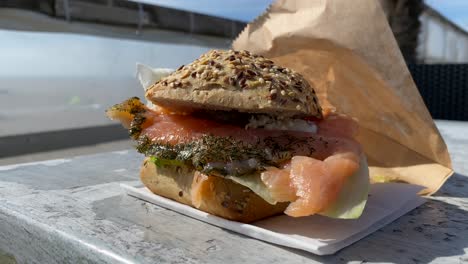 Beach-sandwich-with-smoked-salmon-on-wood-table-by-the-beach