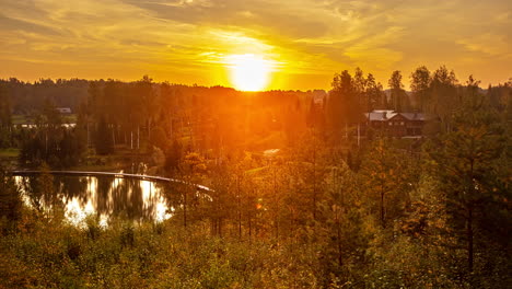 Beautiful-time-lapse-shot-of-golden-morning-sunrise-at-natural-lake-surrounded-by-forestry-in-nature---Bright-sunbeam-shining-at-cloudy-sky---5K-Wildlife-shot