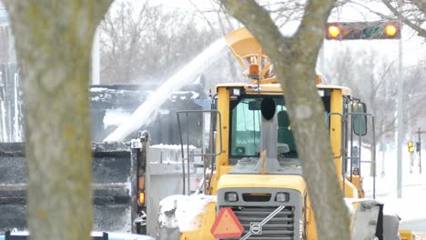 Snowblower-chute-spraying-snow-into-truck,-clearing-snow-from-street
