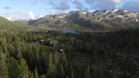 Fliegende-Drohne-über-Traditionellen-Norwegischen-Berghütten-Schieben-In-Richtung-See-4k