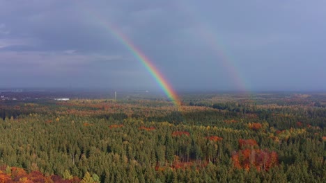 Aerial-of-a-colorful-double-rainbow-over-an-autumn-forest