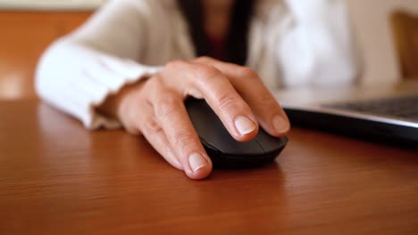 Woman-Hand-Clicking-Computer-Mouse-On-Top-Of-Wooden-Table