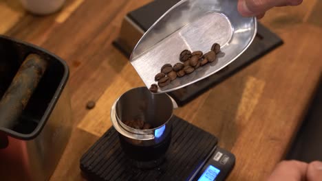 Weighing-roasted-coffee-beans-on-a-scale-to-prepare-a-sample-drink-at-a-roastery,-Handheld-close-up-shot