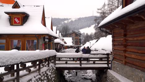 People-standing-on-small-bridge-taking-pictures-in-Zakopane,-Poland-in-winter