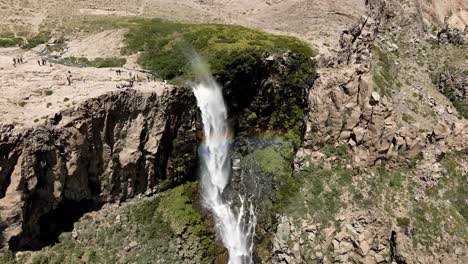 Aerial-orbit-of-the-inverted-waterfall-with-a-constant-rainbow-around-it-in-Maule,-Chile-on-a-sunny-day