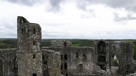 Aerial-forward-over-Llawhaden-Castle-ruins-surrounded-by-green-Welsh-countryside,-UK