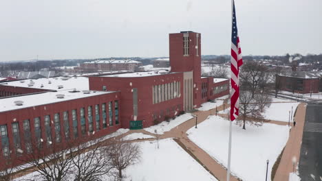 Aerial-establishing-shot-of-large-brick-school-during-snowstorm