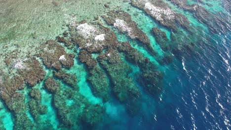 Cinematic-fast-ascending-aerial-video-of-coral-reef-of-Utila-island-in-Honduras