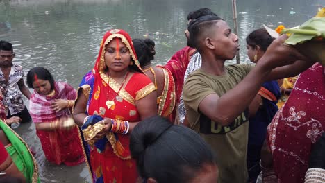 Vista-De-Cerca-De-Una-Mujer-Y-La-Gente-Haciendo-Rituales-Hindúes-De-Pie-En-El-Agua-Del-Río-Ganga-En-Kolkata