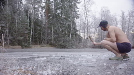 A-hipster-ice-bather-enters-frame-and-begins-axing-the-ice-to-carve-a-hole