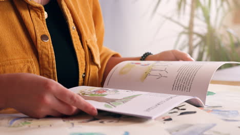Girl-flipping-through-children's-book-on-desk-at-home