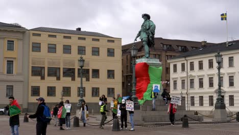Zoom-out-from-Afghan-flag-on-statue,-Afghanistan-people-protesting-in-central-Gothenburg,-Sweden