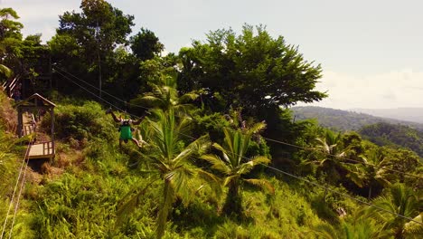 Static-Aerial-Wide-Shot-of-Man-ziplining-Upside-Down-in-A-Tropical-Environment,-Samana,-Dominican-Republic