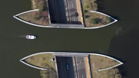 Aerial-TOP-DOWN-Veluwemeer-Aqueduct-view-from-above,-boat-sailing-across-aquaduct-over-traffic-tunnel-highway