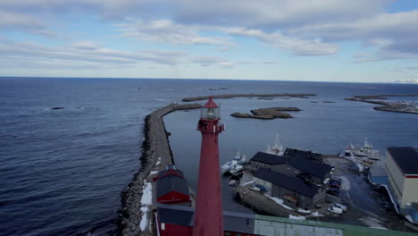 Andenes-Lighthouse-with-view-towards-breakwater-structure,-descending-drone-shot-4k,-Norway