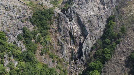 Lichen-covered-massive-cliff-wall-with-stream-fresh-waterfall,-Cascata-da-Frecha-da-Mizarela,-Arouca,-Portugal