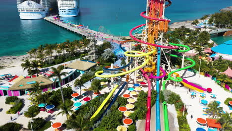 Cinematic-drone-shot-of-CoCoCay-island-with-water-slides-and-a-Royal-Caribbean-cruise-ship-in-the-background