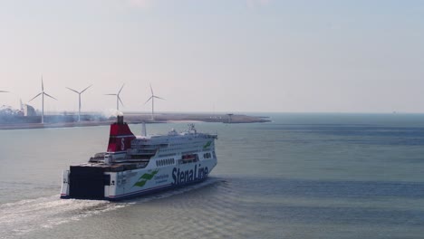 Ferryboat-departs-Rotterdam-seaport,-wind-turbines-in-background