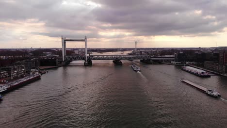 Luftaufnahme-über-Oude-Maas-Mit-Schiffen,-Die-Sich-Der-Eisenbahnbrücke-Spoorbrug-Gegen-Den-Sonnenunterganghimmel-In-Dordrecht-Nähern