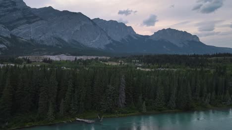 Kananaskis-River-flowing-through-dense-lush-forest-below-the-stunning-Rocky-Mountains-at-blue-hour-in-Alberta,-Canada