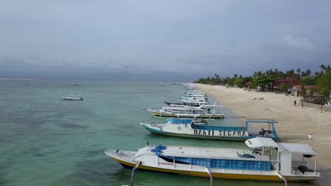 Buttery-soft-aerial-view-flight-fly-backwards-drone-footage-over-local-indonesia-boats-crystal-clear-turquoise-water-at-Mushroom-Bay-lembongan