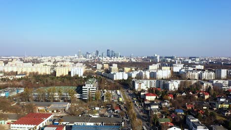 Aerial-drone-view-over-neighborhood-towards-the-Warsaw-skyline,-in-sunny-Poland