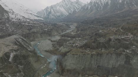 Toma-Aérea-De-La-Vista-Cinematográfica-De-La-Hermosa-Zona-Del-Lago-Attabad,-En-El-Valle-De-Gojal,-Hunza,-Gilgit-Baltistán,-Pakistán-Con-Hermosas-Montañas-Cubiertas-De-Nieve-Y-Un-Río-Helado-Que-Atraviesa-El-Valle