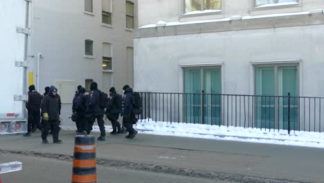 A-large-group-of-Canadian-police-walking-down-the-sidewalk-during-the-Freedom-convoy,-covid-19-protest