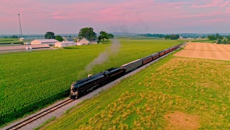 An-Aerial-View-of-an-Antique-Steam-Passenger-Train-Blowing-Smoke-and-Steam-Traveling-Thru-Fertile-Corn-Fields-During-the-Golden-Hour-on-a-Sunny-Summer-Day