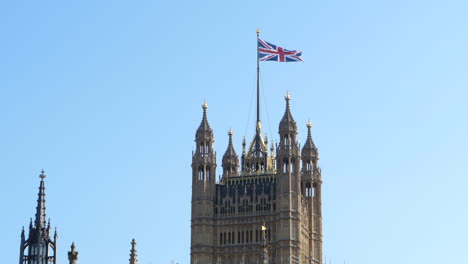 Bandera-De-La-Unión-Británica-En-Cámara-Lenta-Sobre-La-Famosa-Torre-Victoria,-Cielo-Azul