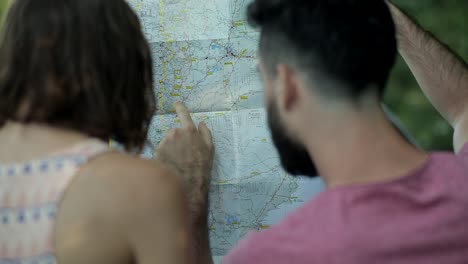 Tourist-Couple-Looking-At-Paper-Map,-Pointing-Finger-At-Route-Location