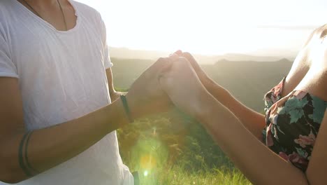 Young-male-and-female-holding-hands-closely-during-sunset,-Close-up-pan-right-shot