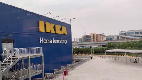 Ikea-Wird-In-Gelb-Auf-Der-Vorderseite-Des-Ladens-Angezeigt,-Der-Sich-Neben-Der-Straße-Befindet,-An-Der-Zahlreiche-Fahrzeuge-Vorbeifahren