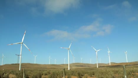 Panorama-De-Turbinas-Eólicas-Girando-Con-Cielo-Azul-En-El-Fondo