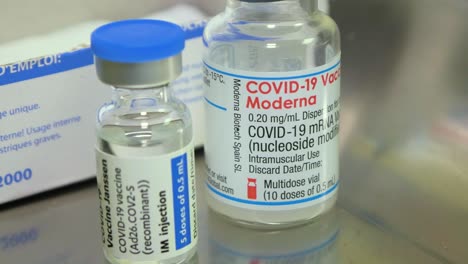 Covid-19-vaccine-jars-and-a-disposable-plastic-syringe,-medical-preparations-in-background