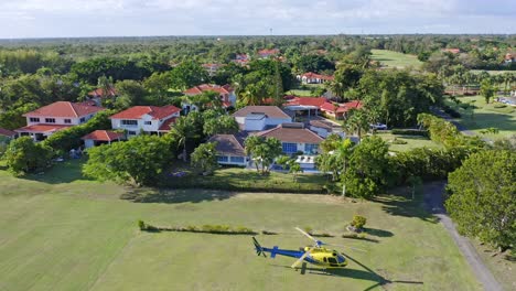Vista-Aérea-De-Villas-En-El-Club-De-Campo-Metro-En-Juan-Dolio,-República-Dominicana,-Pequeño-Helicóptero-Parado-En-El-Césped---Disparo-De-Drones