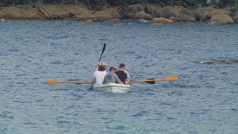 Group-Of-Adult-Men-Leisurely-Bond-Through-Boat-Rowing-In-The-Serene-Beach-Waters-Of-Porthallow,-Cornwall,-England,-United-Kingdom
