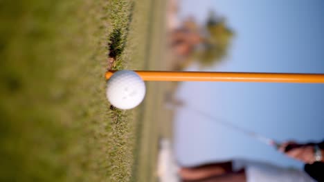 Detail-of-golf-ball-getting-into-a-golf-hole-by-a-caucasian-man