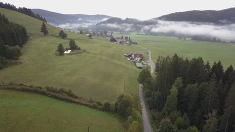 Aerial:-Narrow-one-lane-road-links-farmhouses-in-lush-foggy-valley