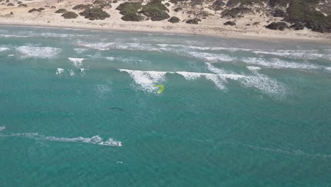 Luftaufnahme:-Einsamer-Kitesurfer-Genießt-Die-Einsamkeit-Vor-Dem-Klaren-Sandstrand